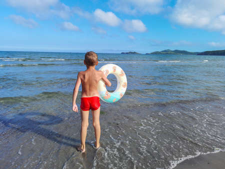 boy with an inflatable circle behind the seaの写真素材