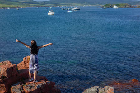 Happy young brunette woman open her arms to the sky and sea and enjoying life . High quality photo