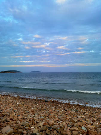 View of beautiful beach with stones, sea and sky in sunny dayの写真素材