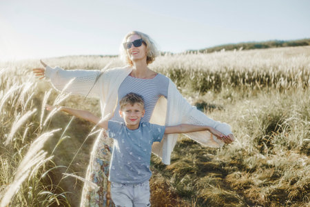 happy mother and son at sunset in a field of ears of cornの写真素材