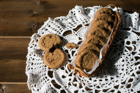 Oatmeal cookies in a wicker basket on a wooden background.