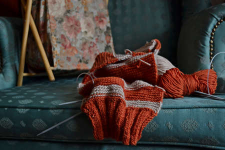 Unfinished knitting needlework on a turquoise colored armchairの写真素材