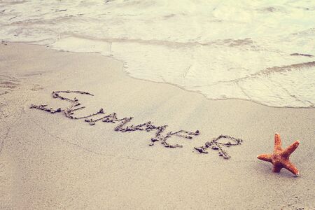 Word summer written in sand on the beach and starfish. Summer holiday, vacation wallpaper, postcard background concept. Vintage imageの写真素材