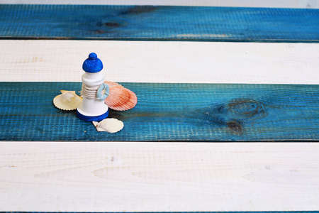 Lighthouse decoration and shells on white and blue wooden rustic marine background.の写真素材