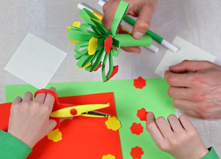 Child cut out of colored paper. Kid making birthday card . Father and son preparing presents for mothers day or 8 march. Kids Art Projects. Happy family conceptの写真素材