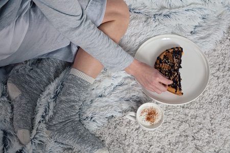Woman wearing cozy warm wool socks relaxing at home, drinking cacao, enjoying her breakfast, belgian waffles with dark chocolate, winter morning concept. Soft, comfy lifestyle.の写真素材