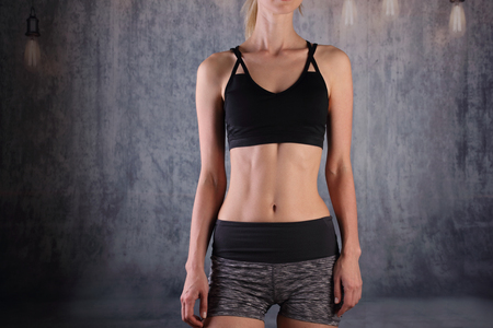 Sport, fit woman. Fit Female dody with perfect abdomen muscles on grey background. Dieting, fitness, active lifestyle concept,の写真素材