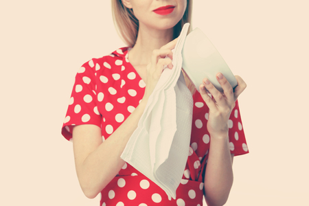 Housekeeping concept. Attractive smiling woman / housewife drying dishes after washing isolated on white backgroundの写真素材