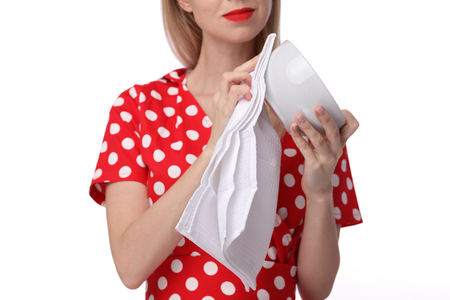 Housekeeping concept. Attractive smiling woman / housewife drying dishes after washing isolated on white backgroundの写真素材