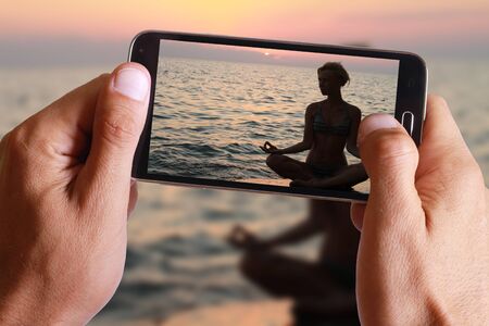 Yoga woman meditatiing in lotus pose on the beach during sunsetの写真素材