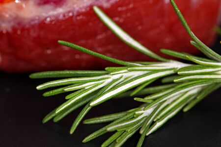 Rosemary and raw meat steak on black background. Fresh, raw, organic vegetables. Cooking, Healthy eating concept.の写真素材