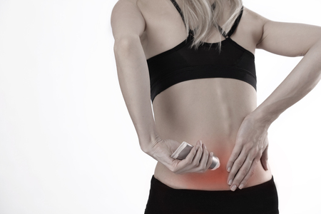 Woman suffering from back pain applying pain relief cream . Sports exercising injury.の写真素材