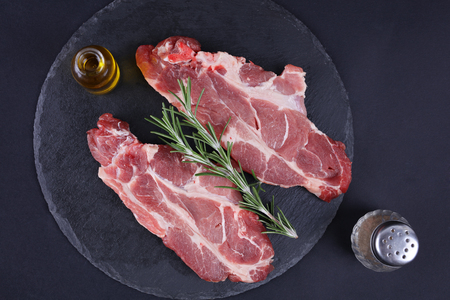 Raw pork loin chops black background, spices, olive oil. Cooking background, healthy eating concept.の写真素材