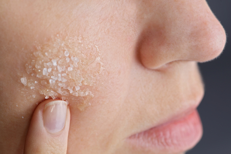 Woman applying homemade facial scrub from honey and sea salt. Skin care conceptの写真素材