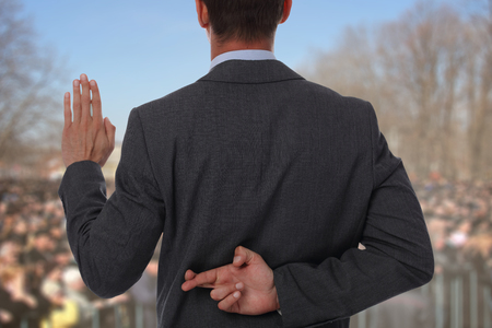Politician liar gives people impossible promises with fingers crossed on his back.の写真素材