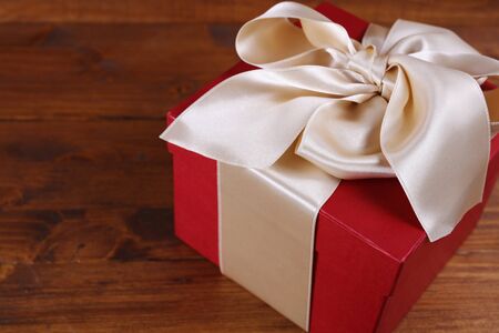 Red present box with Ribbon on wooden background. Gift box packaging. Birthday, New year, Valentine's Day, 8 march, Christmas concept, copy spaceの写真素材