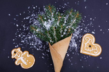Waffle cone christmas wirh tree branches and ginger cookies on dark background. New year concept backgroundの写真素材