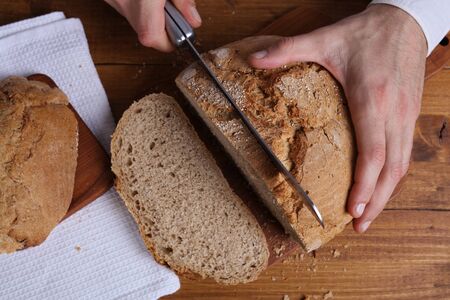 Man cutting tasty fresh whole grain bread. Healthy eating conceptの写真素材