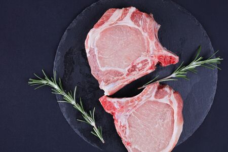 Raw pork loin chops black background, spices, olive oil. Cooking background, healthy eating concept.の写真素材