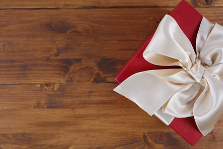 Red present box with Ribbon on wooden background. Gift box packaging. Birthday, New year, Valentine's Day, 8 march, Christmas concept, copy spaceの写真素材