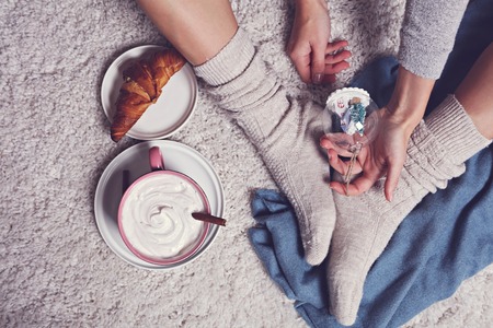 New year concept, lazy winter morning , cozy woman holding christmas tree decoration and enjoying breakfast and hot cocoa drinkの写真素材