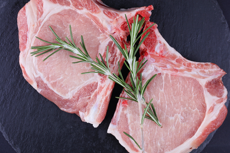 Raw pork loin chops black background, spices. Cooking background, healthy eating concept.の写真素材