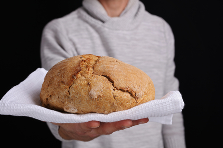 Man holding or giving bread as a welcome. Baker offer loaf of tasty fresh breadの写真素材