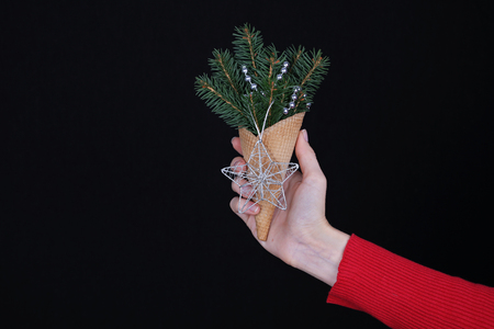 Woman holding waffle cone with composition made from christmas tree branches. New year concept background, copy spaceの写真素材