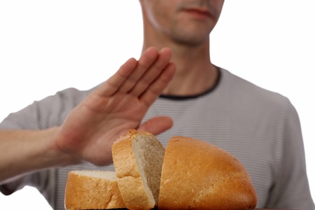 Gluten intolerance and diet concept. Man refuses to eat white bread. Selective focus on breadの写真素材