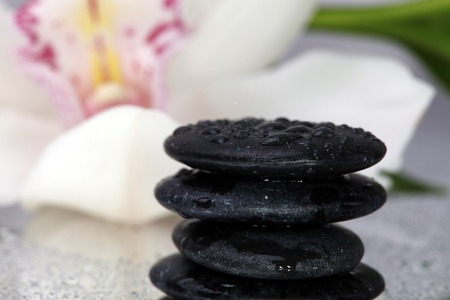 Spa background. Volcanic rock, bamboo and orchids on reflective background with raindrops....