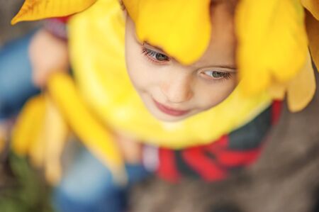 Little girl 3 years old in a yellow vest and wreath of yellow autumn leaves on her head. Conceptual...