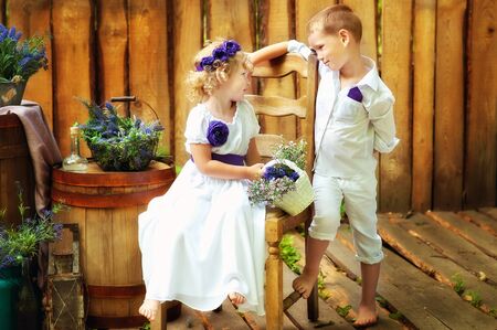Small boy and girl in white clothes in rustic style decorations. Eco family. Organic and ecological lifestyle in childhood. Brother and sister look at each other. Summertime.の写真素材