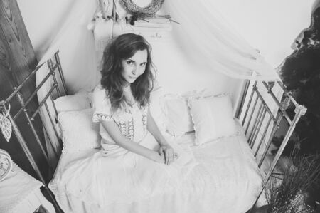 Black and white portrait of attractive young woman with sensual look in camera sitting in bed. Girl waiting for spring. Copy space. Space for textの写真素材