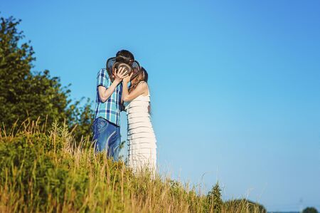 Happy married couple kiss each other behind hat on hill in summer. Blue sky and copy space for text. Faceless people in love together. Men and women kissing anonymous. Romantic in countryside.の写真素材