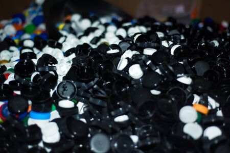 Waste heap from plastic bottle caps on waste sorting station. Large pile of colored stoppers...