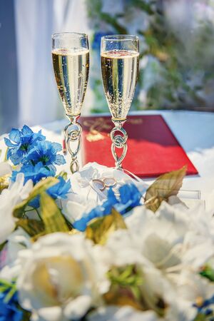 Vertical picture of wedding glasses with champagne, bride and groom rings and wedding decorations in summer sunny wedding day. Wedding and happiness conceptの写真素材