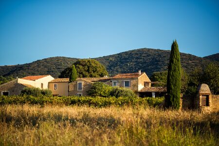 Old traditional stone provencale farmyard in Provence, France with Luberon hill on background in hot summer morning with clear blue sky. Travel tourism destination Provence.の写真素材
