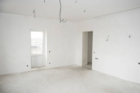 Interior construction of housing project with drywall installed and patched without painting applied, plastered walls and electrical wiringの写真素材
