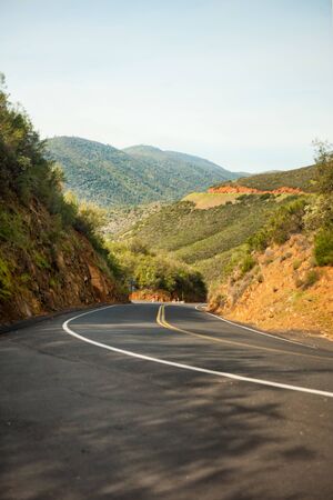 Vertical picture of mountain road in Yosemite national park, California, USA with hills around in sunny summer day. Yosemite valley travel tourism destination. Transportation by car to Yosemite.の写真素材