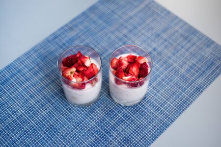Layered strawberry homemade italian creamy dessert panna cotta with fresh berries in two glasses on blue background. Organic sweet. Top view of strawberry panna-cotta.の写真素材