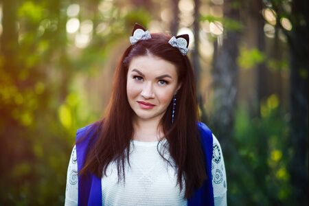 Portrait of beautiful smiling brunette 30 years old woman in funny ears in forest on sunset time. Freedom, happiness, close to nature. Outdoors photoshoot. Make-up for skin with open large poresの写真素材