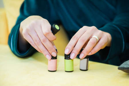 Aromatherapy. Girls hand with beautiful skin holds one bottle of essential oil and touches three bottles. Close up. Organic healthcare and wellness treatment.の写真素材