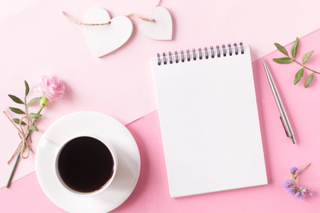 Notebook with clean page, cup of coffee, flower, pen and wooden heart on pink background. Top view, flat lay style.の写真素材