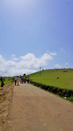 Ooty,Tamilnadu,India-June 04 2022:Tourists enjoying beautiful green elevated lawn in ooty shooting...