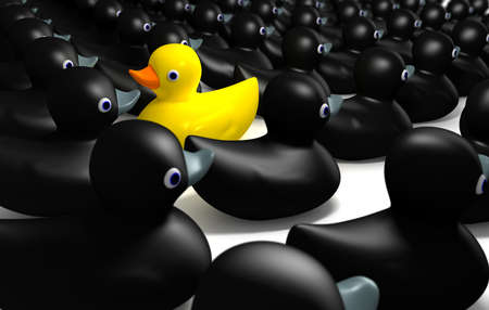 A non-conformist depiction of a yellow rubber bath duck swimming against the flow of black rubber ducks.の写真素材