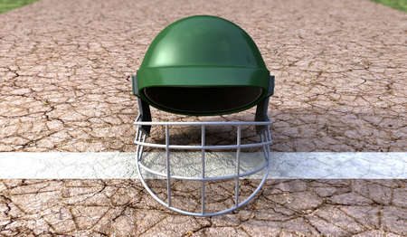 A regular green plastic cricket helmet on a cracked cricket pitch with white markingsの写真素材