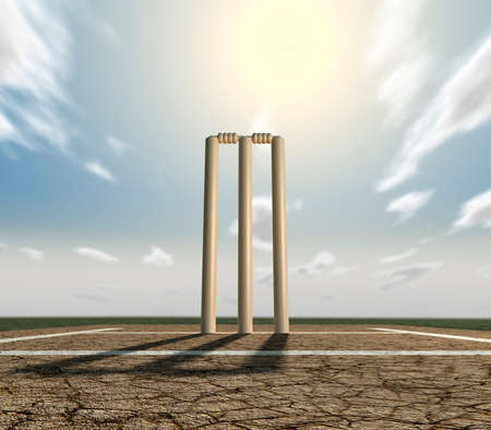 A set of cricket wickets set up on a cracked cricket pitch with white markings on a blue sky backgroundの写真素材