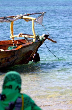 A traditional dhow sail boat on emerald blue water alongside a sandy white beach in Zanzibarの写真素材