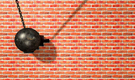 A regular metal wrecking ball attached to a chain hitting and breaking a face brickの写真素材