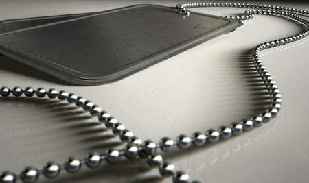 A regular set of blank military dog tag identity tags attached to a chain draped on an isolated backgroundの写真素材